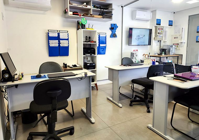 Recepção da Híbrido com mesas de atendimento e organizadores de check-in, orçamento e entrega